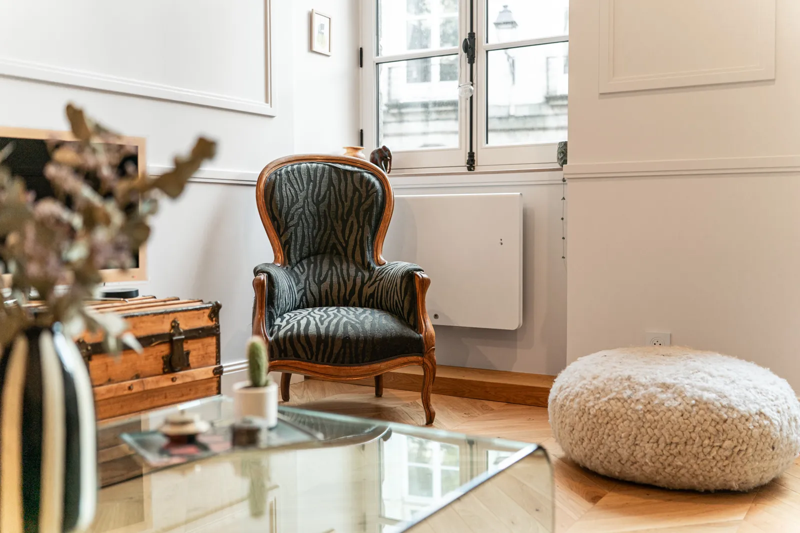 Salon d’un appartement ancien, fauteuil de style et murs clairs